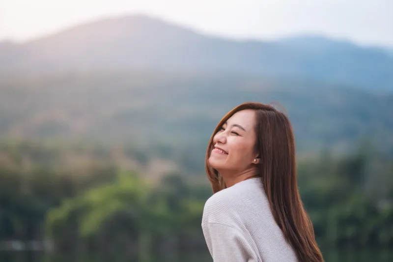 Thoughtful Filipino woman gazing upward in outdoor mountain setting.