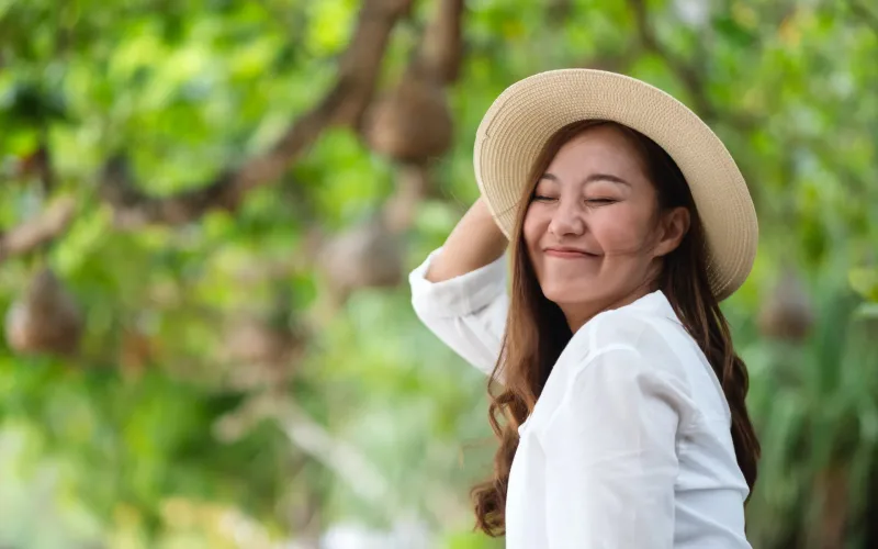 Thoughtful Asian woman in nature setting with peaceful expression, reflecting the significance of family relationships in Filipino culture.
