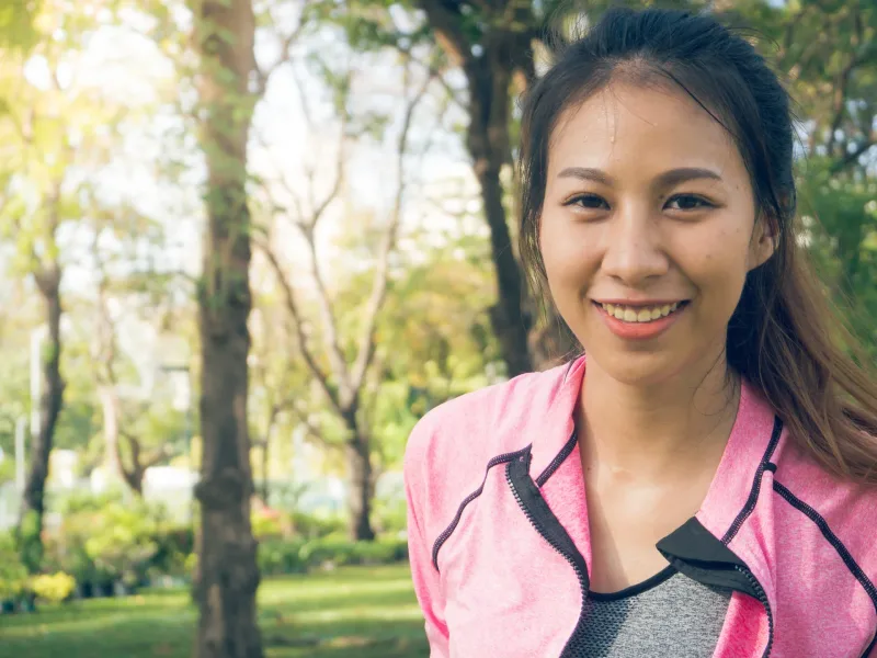 Woman smiling outdoors in athletic wear, embodying independent and autonomous travel choices