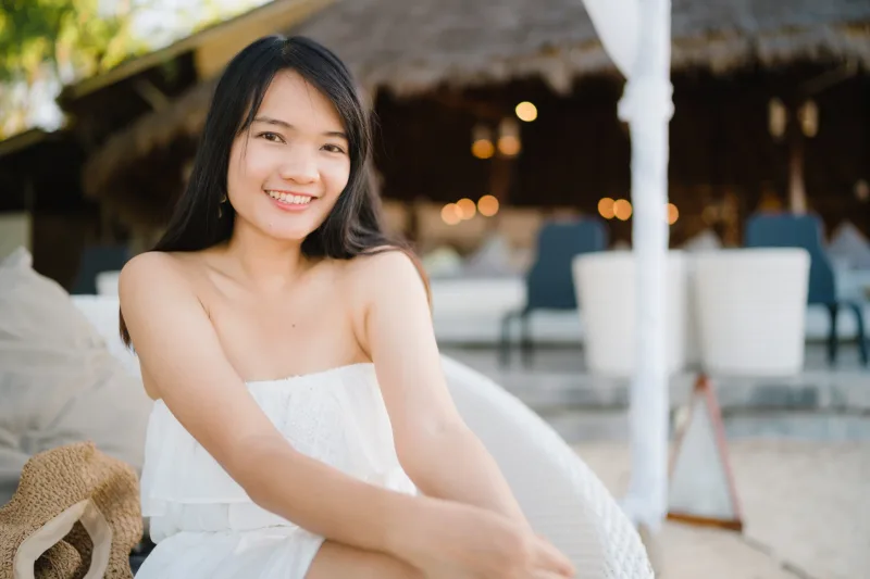 Young woman smiling genuinely in tropical resort setting near pool