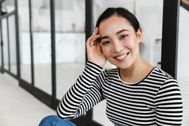 Woman in striped shirt smiling warmly in bright home setting