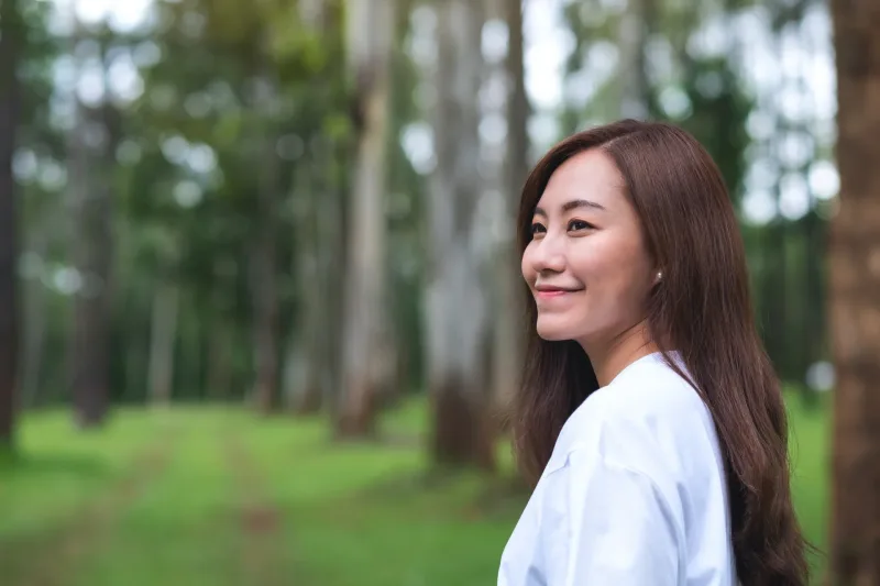Woman standing peacefully outdoors with thoughtful natural expression