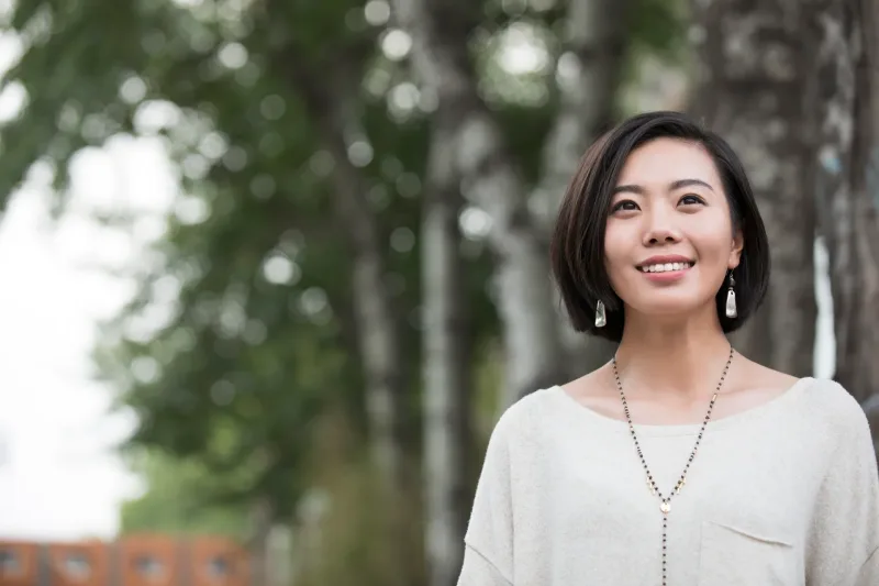 Woman smiling outdoors near trees in peaceful urban setting
