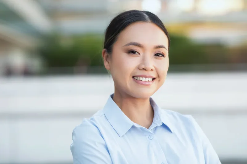 Young Asian woman smiling outdoors with natural lighting, representing the warm personality traits Filipinas bring to genuine connections
